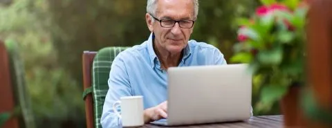 Oude man aan laptop – buitenshuisverzekering – particulier