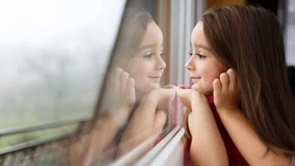 Meisje kijkt door raam – Woonhuisverzekering – Particulier