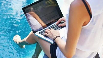 Vrouw werkt op laptop aan het water-reisverzekering-particulier