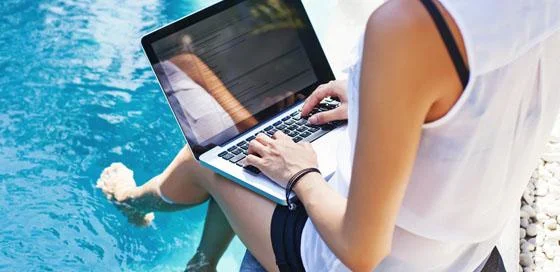 Vrouw werkt op laptop aan het water-reisverzekering-particulier