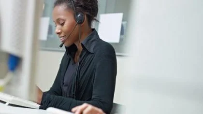 Vrouw op werk belt met head set – AVG – Zakelijk