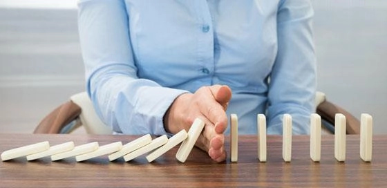 Vrouw houdt vallende dominostenen tegen – BRV – Zakelijk