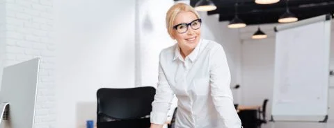 Vrouw met bril staat achter bureau – Computerverzekering – Zakelijk