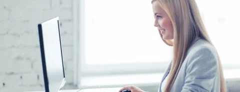 Vrouw achter bureau op computer – Cybercrime verzekering – Zakelijk