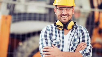 Werkman met helm op lacht – Ziekengeldverzekering – Zakelijk