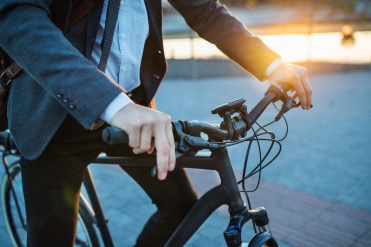 Man in pak op elektrsiche fiets – Bedrijfsaansprakelijkheidsverzekering – Zakelijk