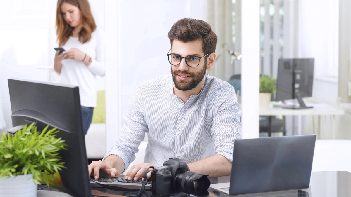 Man met bril achter bureau op computer – Goederen- en inventarisverzekering – Zakelijk