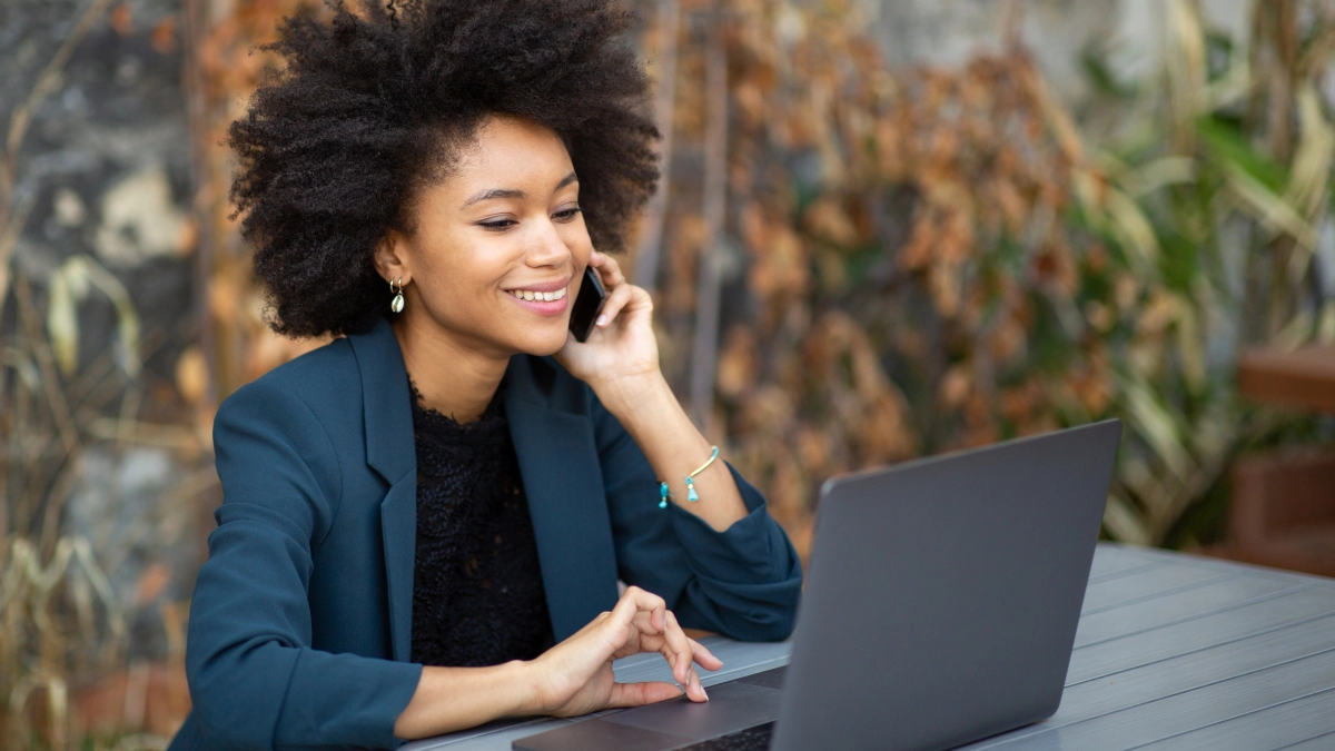 Vrouw buiten aan telefoon achter laptop – Hypotheek – Zakelijk