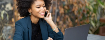 Vrouw buiten aan telefoon achter laptop – Hypotheek – Zakelijk