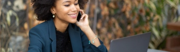 Vrouw buiten aan telefoon achter laptop – Hypotheek – Zakelijk