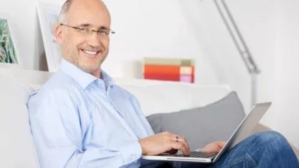Man op laptop glimlacht – Pensioen en inkomen – Particulier