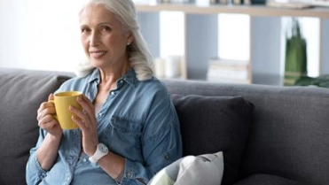 Oudere vrouw met kopje drinken op bank – Pensioen en inkomen – Particulier