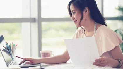 Vrouw achter bureau op laptop – Reconstructieverzekering – Zakelijk