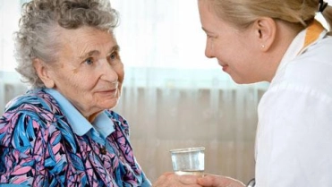 Oudere vrouw krijgt water van verpleegster – Specialismen – Zakelijk