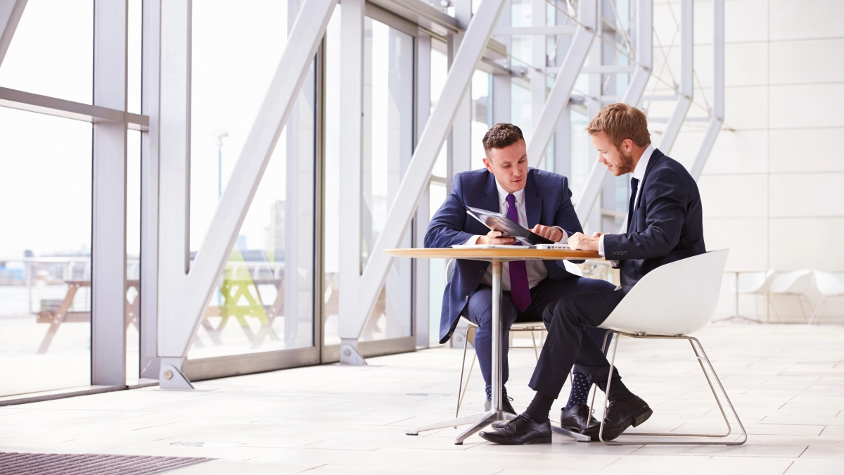 Mannen aan tafel in gebouw – Ziekengeldverzekering – Zakelijk