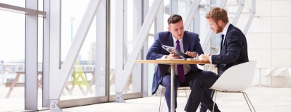 Mannen aan tafel in gebouw – Ziekengeldverzekering – Zakelijk