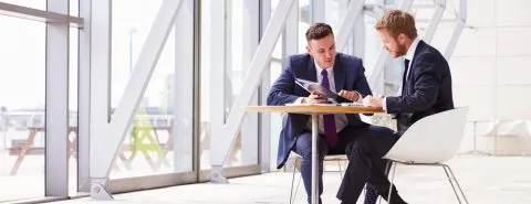 Mannen aan tafel in gebouw – Ziekengeldverzekering – Zakelijk