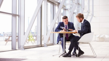 Mannen aan tafel in gebouw – Ziekengeldverzekering – Zakelijk