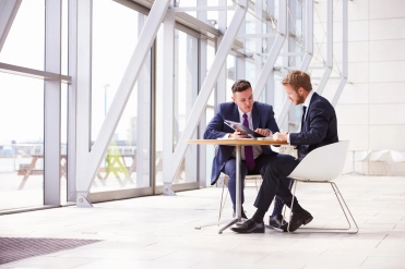 Mannen aan tafel in gebouw – Ziekengeldverzekering – Zakelijk