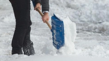 Vrouw schept sneeuw met sneeuwschep – Gebouwenverzekering – Zakelijk