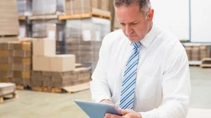 Man in magazijn bekijkt I-pad – Gebouwenverzekering – Zakelijk