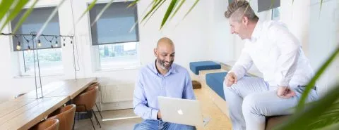 Man op laptop en man kijkt mee vanaf bankje – Werken bij Zicht
