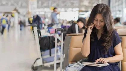 Vrouw aan telefoon op vliegveld – Werknemersschadeverzekering – Zakelijk