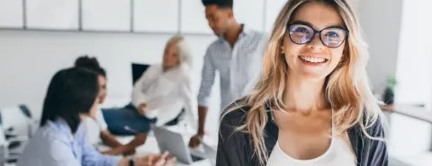 Vrouw lacht, mensen op achtergrond – Werknemersschadeverzekering – Zakelijk