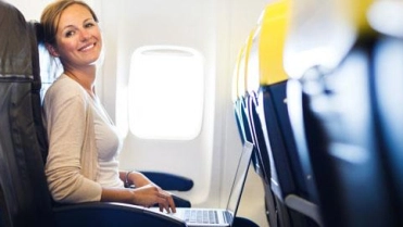 Vrouw in vliegtuig met laptop – Zakelijke reisverzekering – Zakelijk
