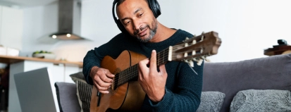 Relaxed,Man,Playing,The,Guitar,At,Home,And,Using,A