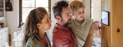 Family,Looking,At,Smart,Thermostat,,Adjusting,,Lowering,Heating,Temperature,At