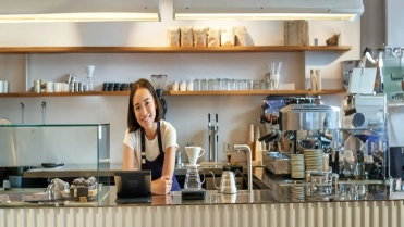 Happy,Smiling,Asian,Barista,,Girl,Behind,Counter,,Working,With,Pos