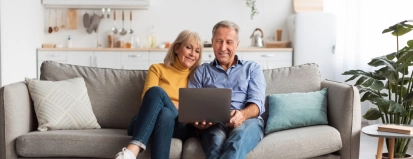 oud stel op bank starend naar laptop