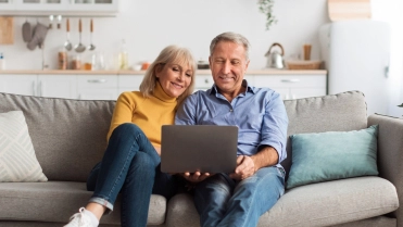 oud stel op bank starend naar laptop