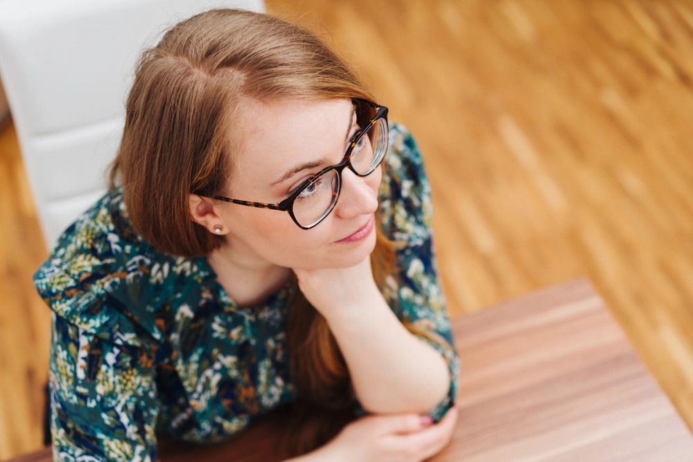 Thoughtful,Attractive,Young,Woman,Sitting,Cupping,Her,Chin,In,Her