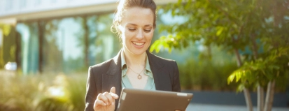 happy woman worker near office building using digital tablet